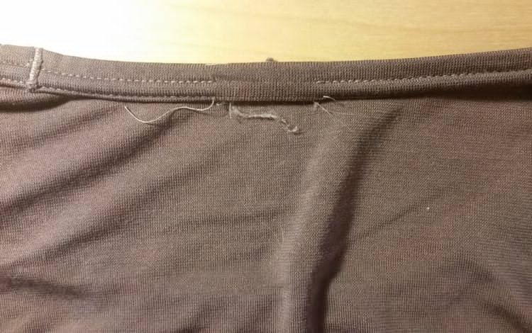 Structural threads seen from the back are cut and loose after removing the shirt tag Structural threads seen from the back are cut and loose after removing the shirt tag